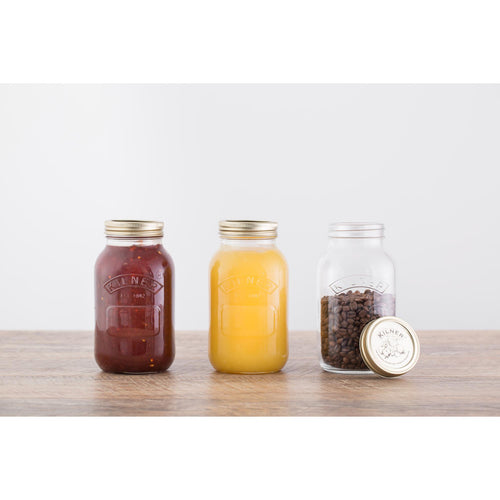 Three glass jars with metal lids on a wooden surface against a white background