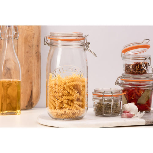Glass jars with pasta and spices on a kitchen counter