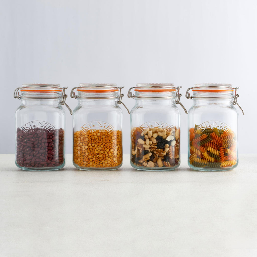 Four glass jars with various dry goods on a white background