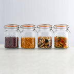 Four glass jars with various dry goods on a white background