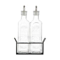 Two glass bottles with metal lids in a black metal stand on a white background