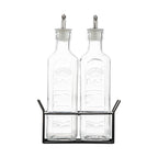 Two glass bottles with metal lids in a black metal stand on a white background