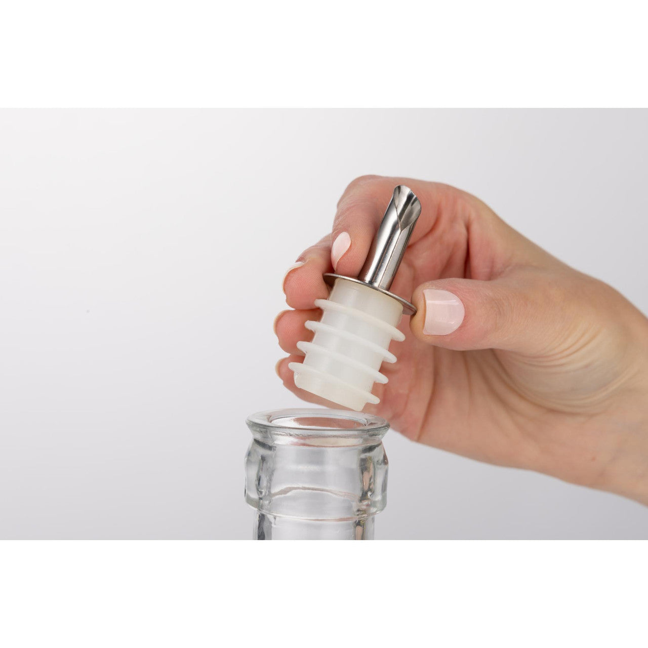 Hand holding a bottle stopper over a glass bottle on a white background