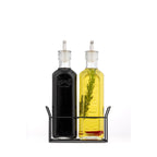 Two glass oil bottles with black stands on a white background