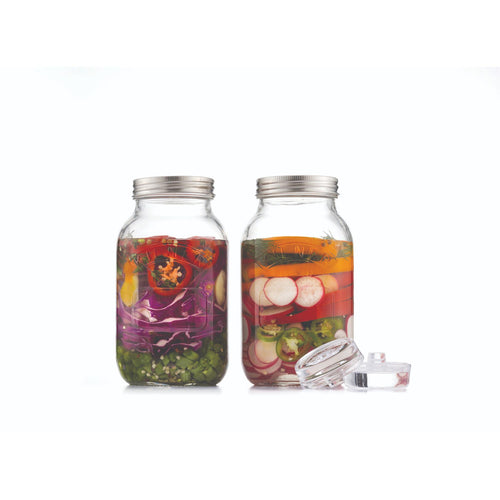 Two glass jars with metal lids containing pickled vegetables on a white background