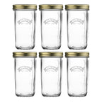 Set of six clear glass jars with gold lids on a white background