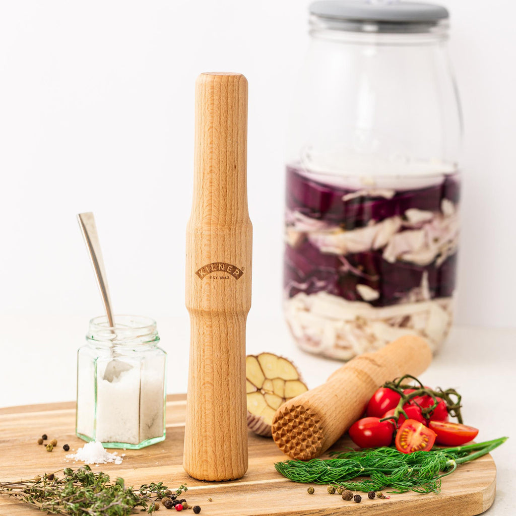Wooden kitchen tool on a wooden board with ingredients and jars in the background
