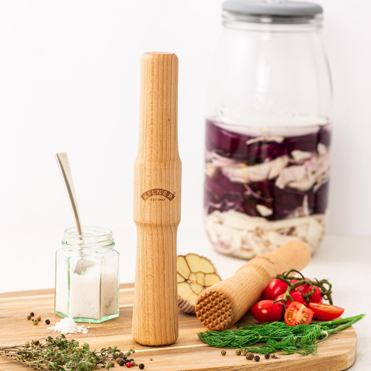 Wooden kitchen tool on a wooden board with ingredients and jars in the background
