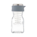 Clear glass bottle with a gray silicone lid on a white background