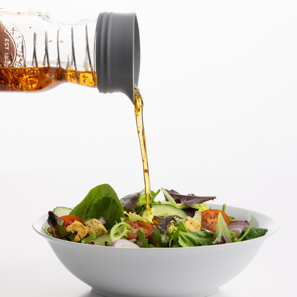 Bowl of salad with a bottle pouring dressing onto it