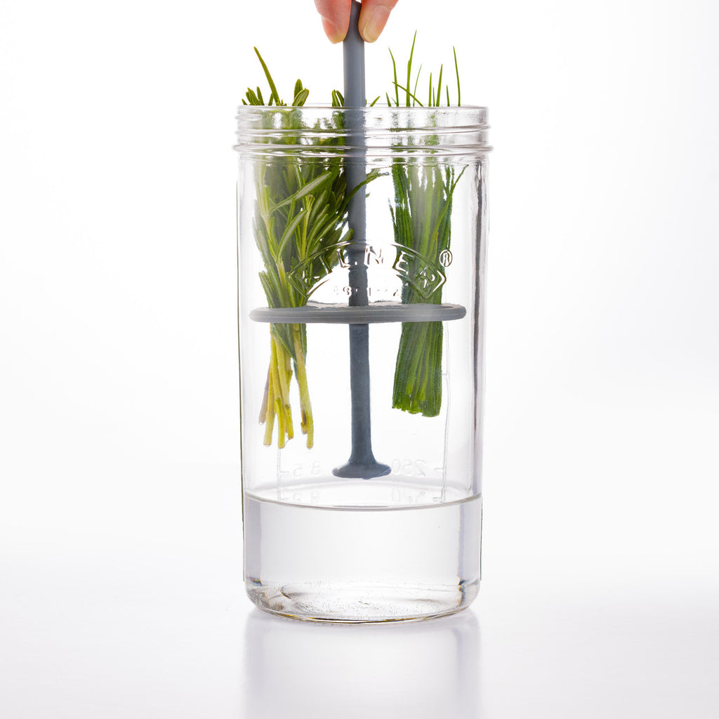 Clear glass tumbler with grass and a straw on a white background