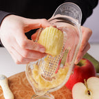 Person using a potato peeler to peel a potato with apples in the background
